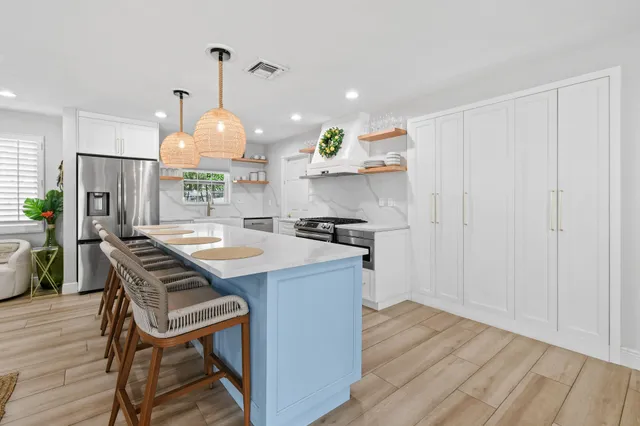 a large white kitchen with a large island oven a stove and a wooden floors