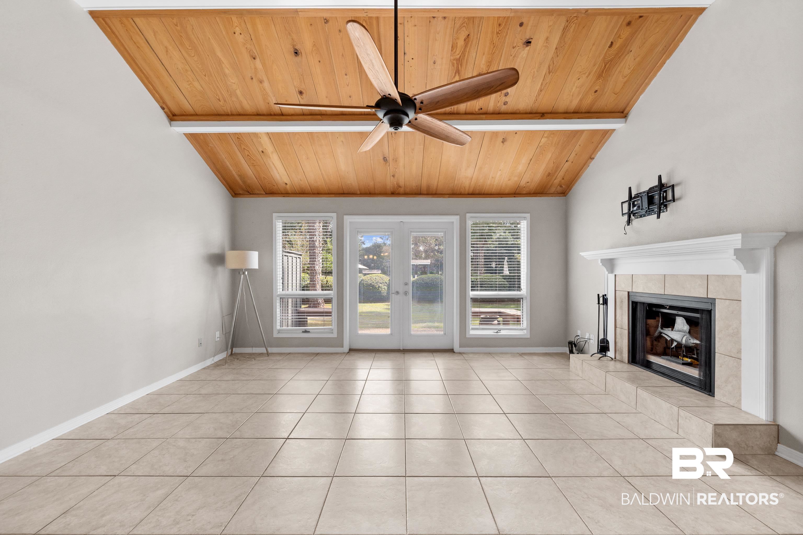 1701 Regency Road, Unit 111 Gulf Shores, AL 36542 - Photo 5 of 29 Unfurnished living room featuring wood ceiling, a fireplace, light tile patterned floors, and ceiling fan