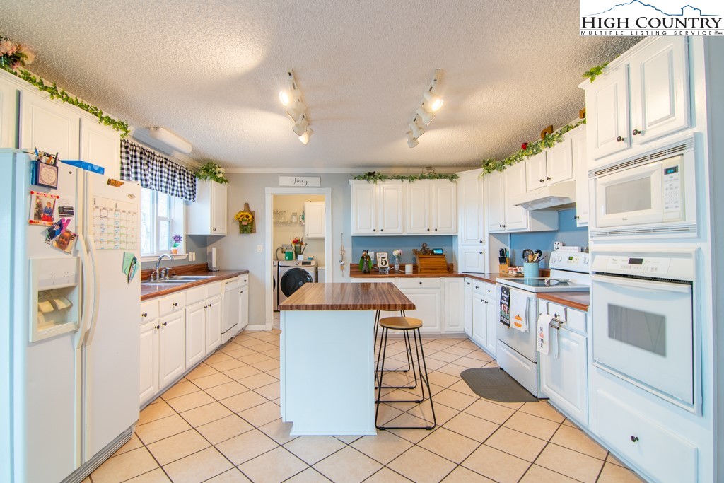 8877 Glade Valley Road Ennice, NC 28623 - Photo 28 of 49 a kitchen with white cabinets and white appliances