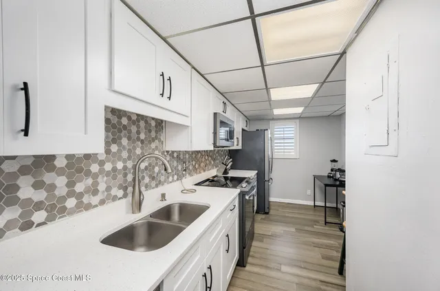 a kitchen that has a sink and a stove with wooden floor