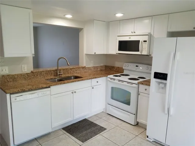 a kitchen with stainless steel appliances granite countertop white cabinets a sink and a oven