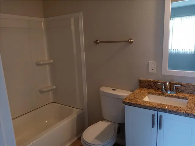 a bathroom with a granite countertop toilet sink and mirror