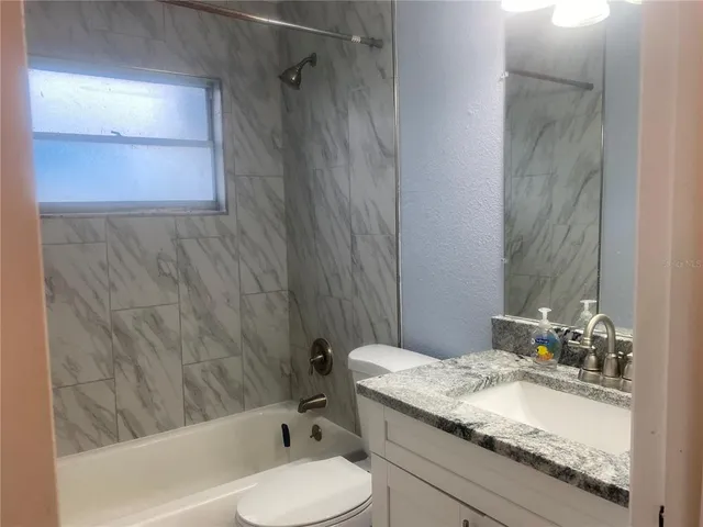a bathroom with a granite countertop sink toilet and shower