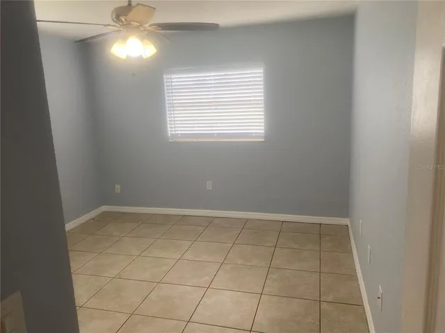 en empty room with windows and chandelier fan