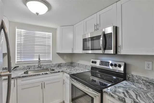 a kitchen with stainless steel appliances granite countertop a stove a sink and a microwave