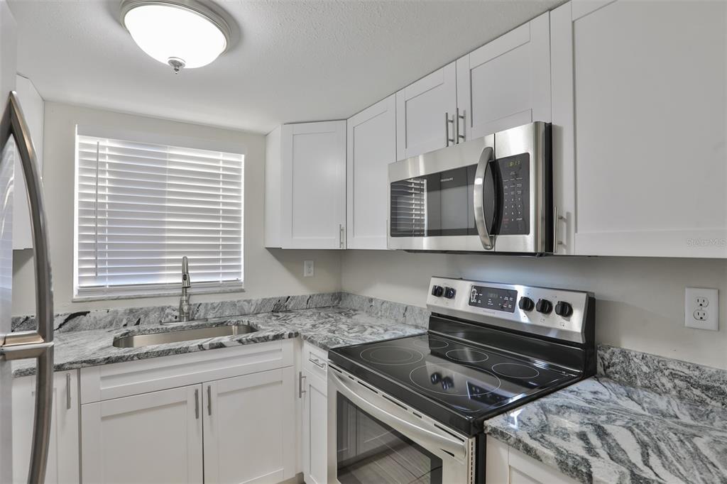 9925 Grace Drive Port Richey, FL 34668 - Photo 5 of 14 a kitchen with stainless steel appliances granite countertop a stove a sink and a microwave