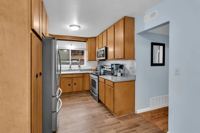 a kitchen with stainless steel appliances granite countertop a stove a sink and a refrigerator