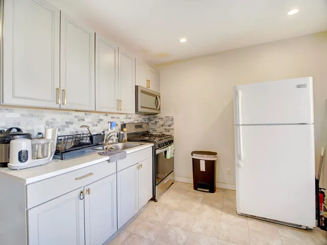 a kitchen with stainless steel appliances granite countertop a refrigerator sink and white cabinets