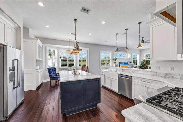 a kitchen with a table chairs refrigerator and wooden floor