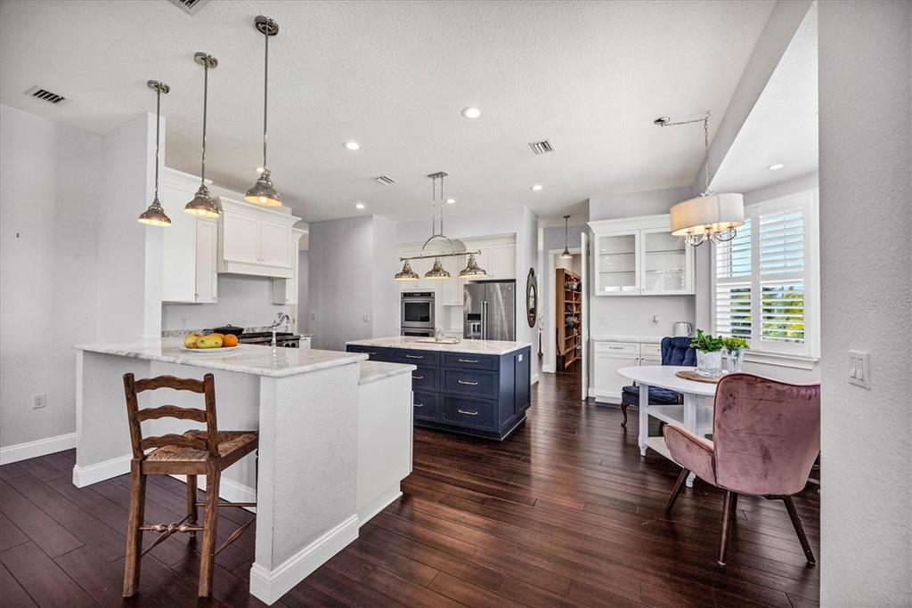 10050 Creekside Drive Placida, FL 33946 - Photo 12 of 52 a kitchen with a table chairs refrigerator and wooden floor