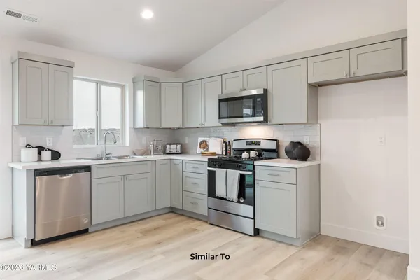 a kitchen with stainless steel appliances granite countertop a stove a sink and a microwave