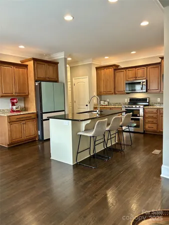 a kitchen with stainless steel appliances a stove a sink a microwave a refrigerator a dining table and chairs