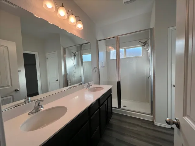 a bathroom with a double vanity sink mirror and shower