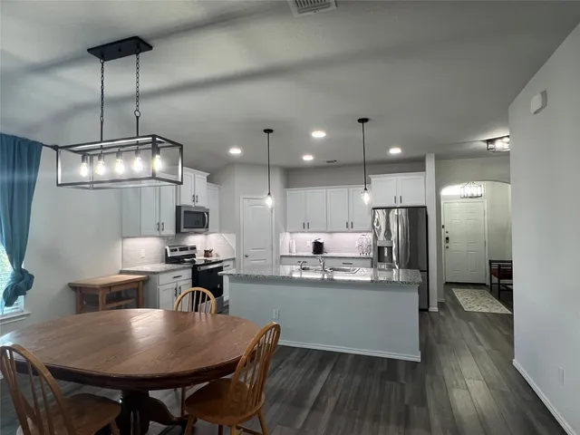 a kitchen with stainless steel appliances granite countertop a kitchen island a stove a table and chairs