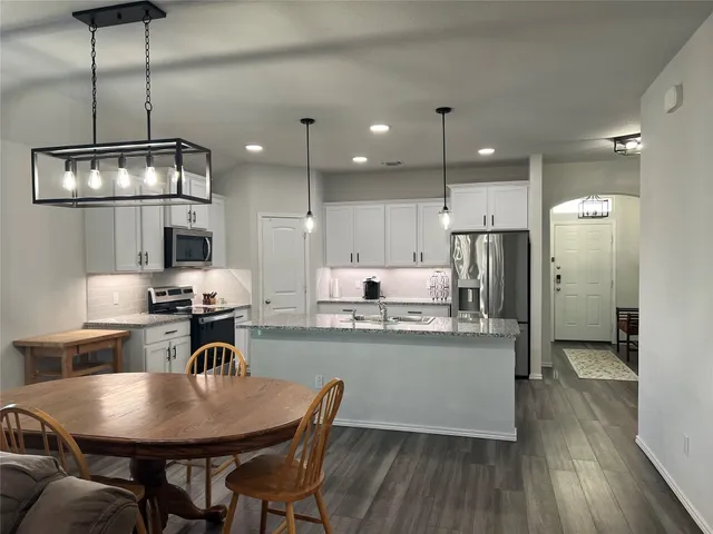 a kitchen with stainless steel appliances granite countertop a kitchen island a stove a table and chairs