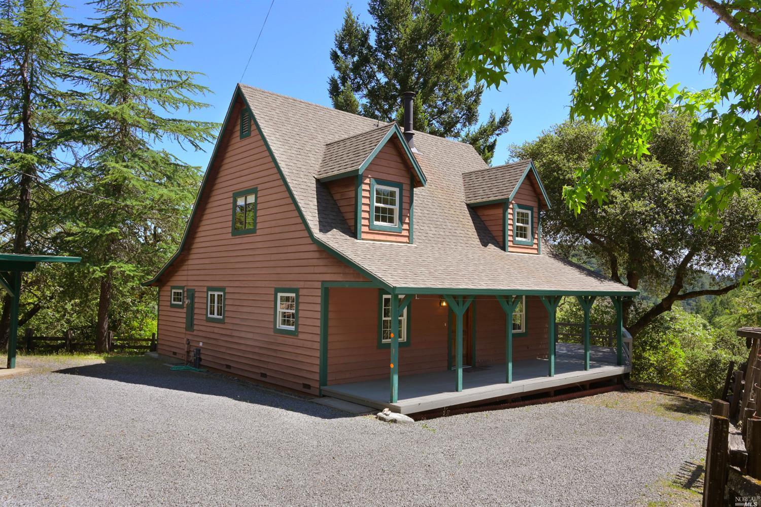 a view of a house with a yard plants and large tree