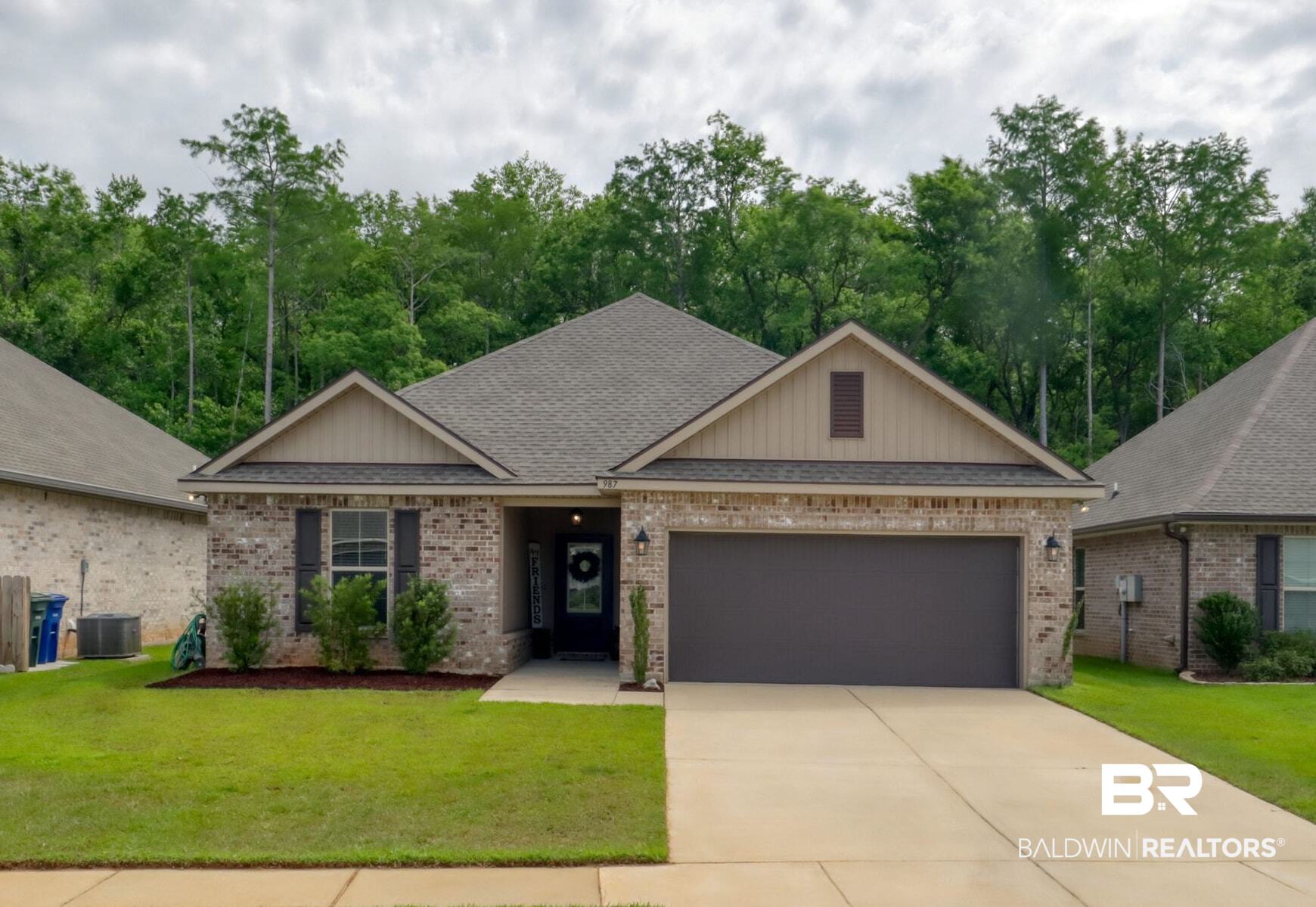 987 Gibson Court Foley, AL 36535 - Photo 3 of 34 View of front facade with brick siding, central AC, a front lawn, concrete driveway, and an attached garage