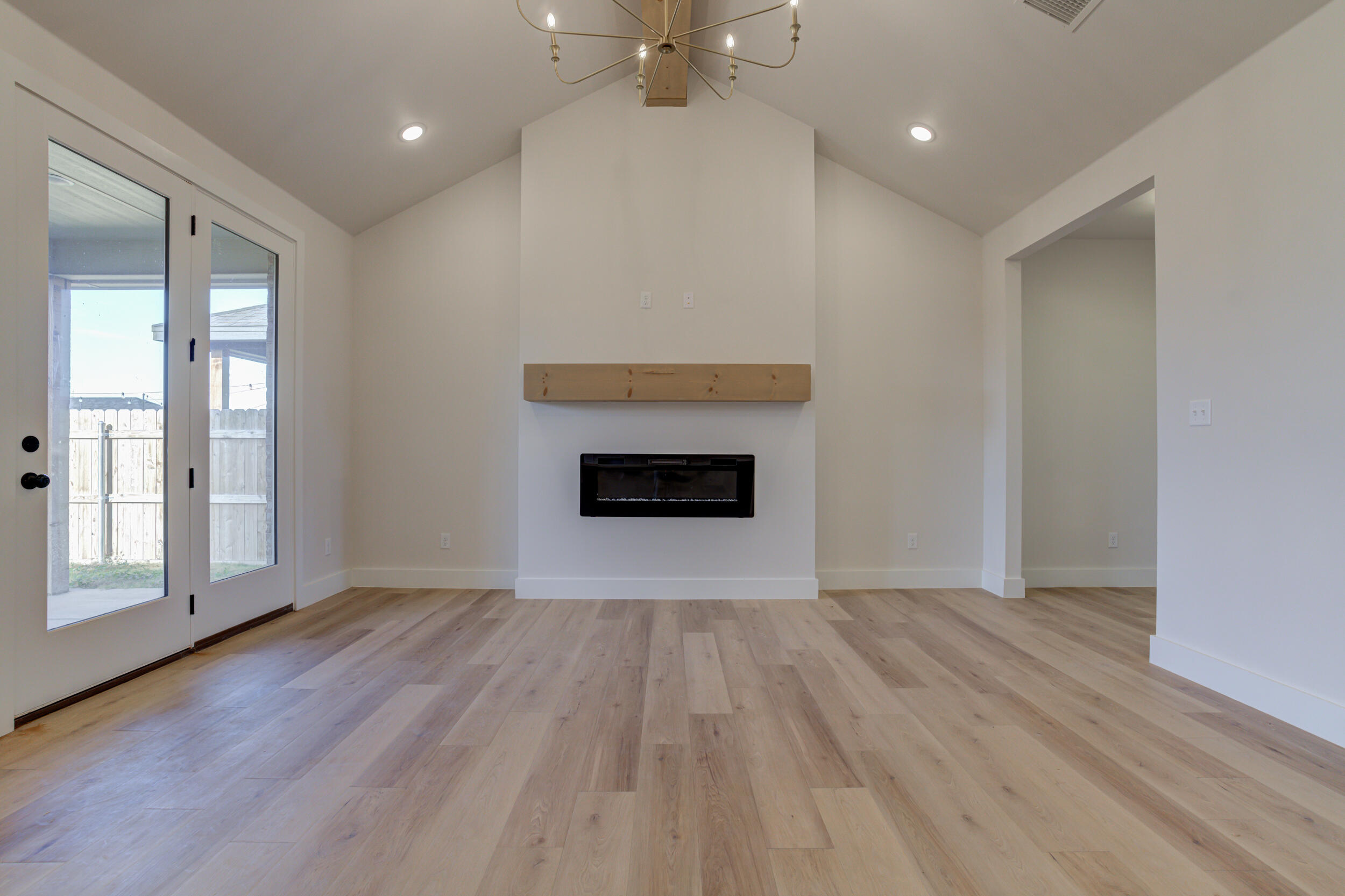 6913 13th Street Lubbock, TX 79416 - Photo 11 of 45 wooden floor fireplace and windows in an empty room