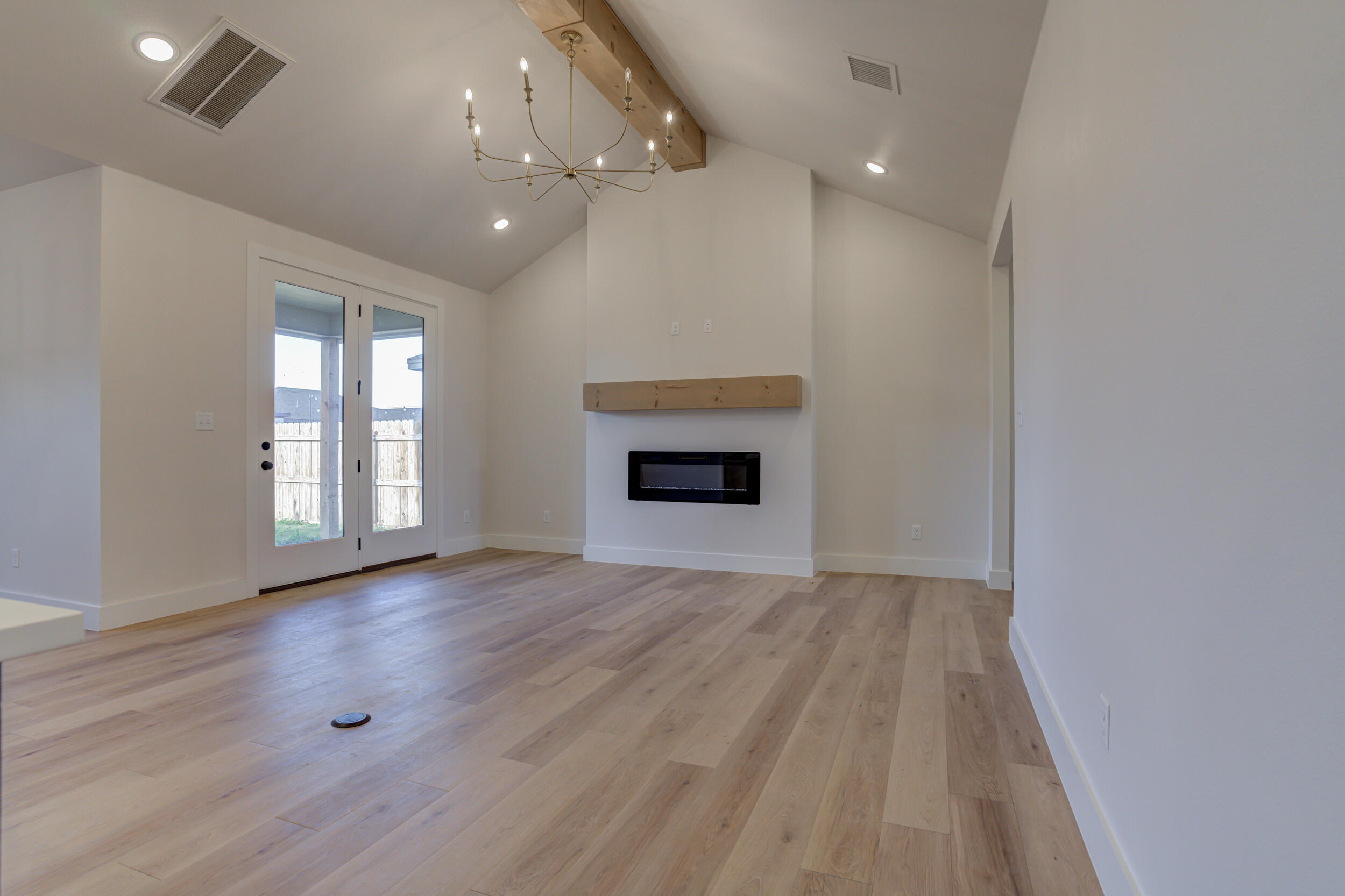 6913 13th Street Lubbock, TX 79416 - Photo 9 of 45 an empty room with wooden floor fireplace and windows