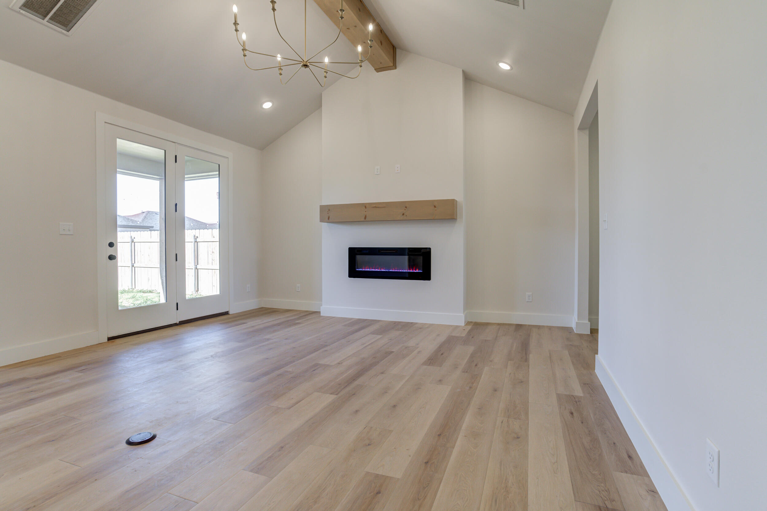6913 13th Street Lubbock, TX 79416 - Photo 10 of 45 an empty room with wooden floor fireplace and windows