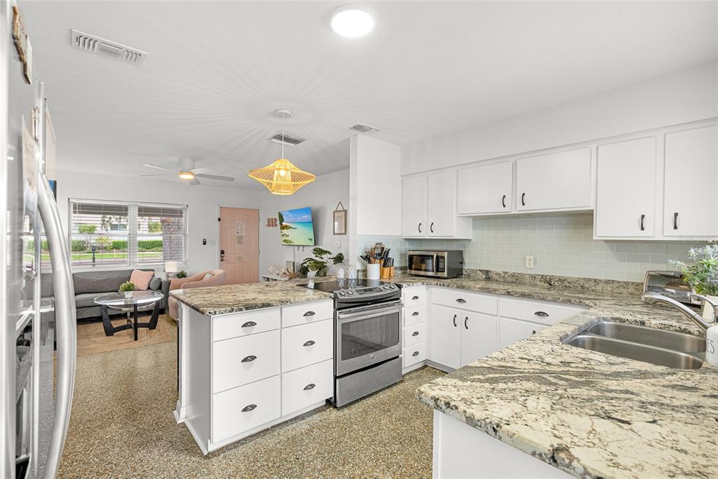 4939 100th Way North St. Petersburg, FL 33708 - Photo 12 of 43 a kitchen with a stove a sink a oven a dining table and chairs
