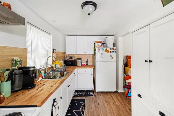 a kitchen with refrigerator a stove and wooden floor