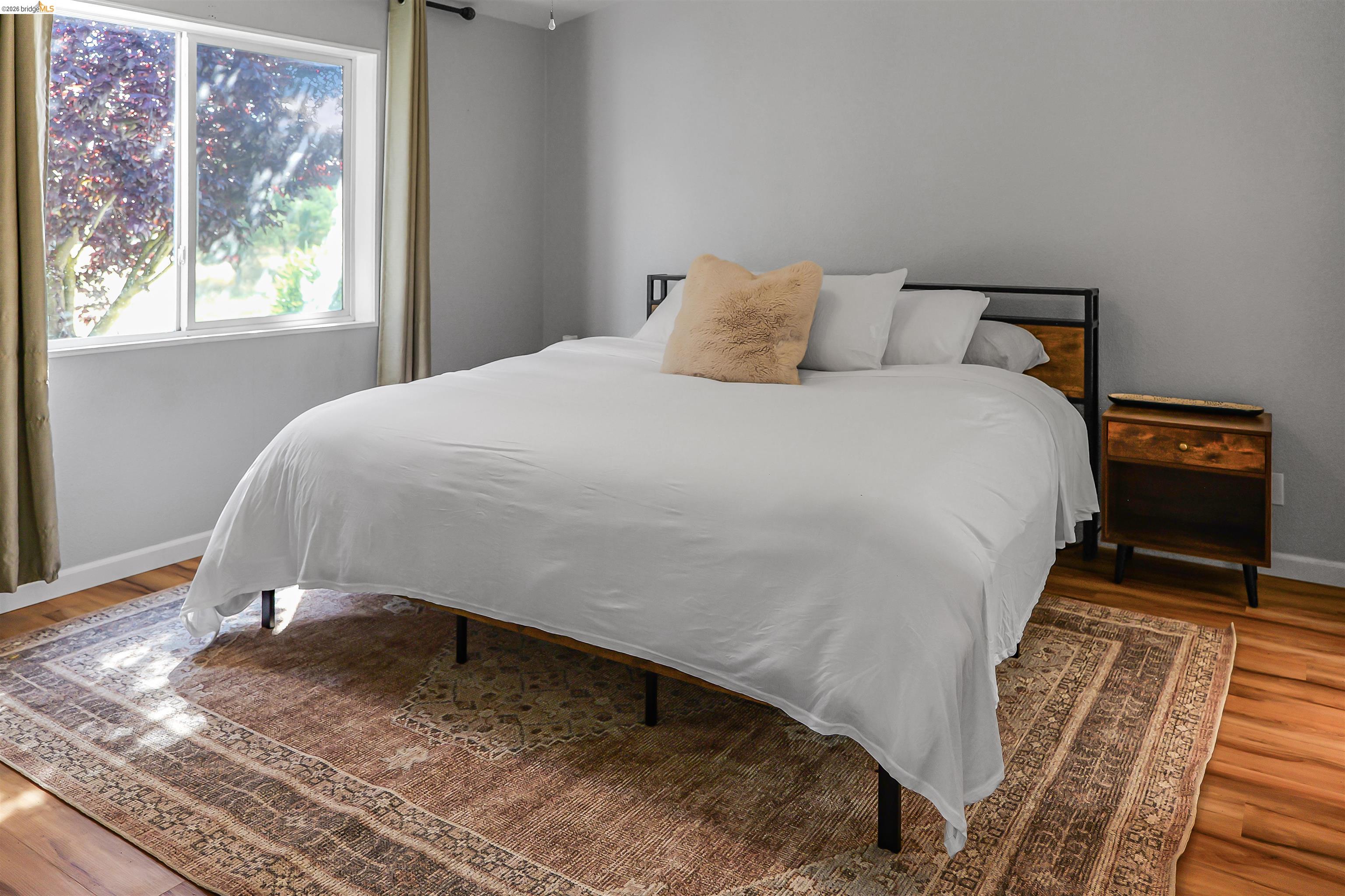 4419 Little John Road Copperopolis, CA 95228 - Photo 12 of 43 Bedroom featuring a large window, light gray walls, wood-finish flooring, and a built-in metal and wood headboard