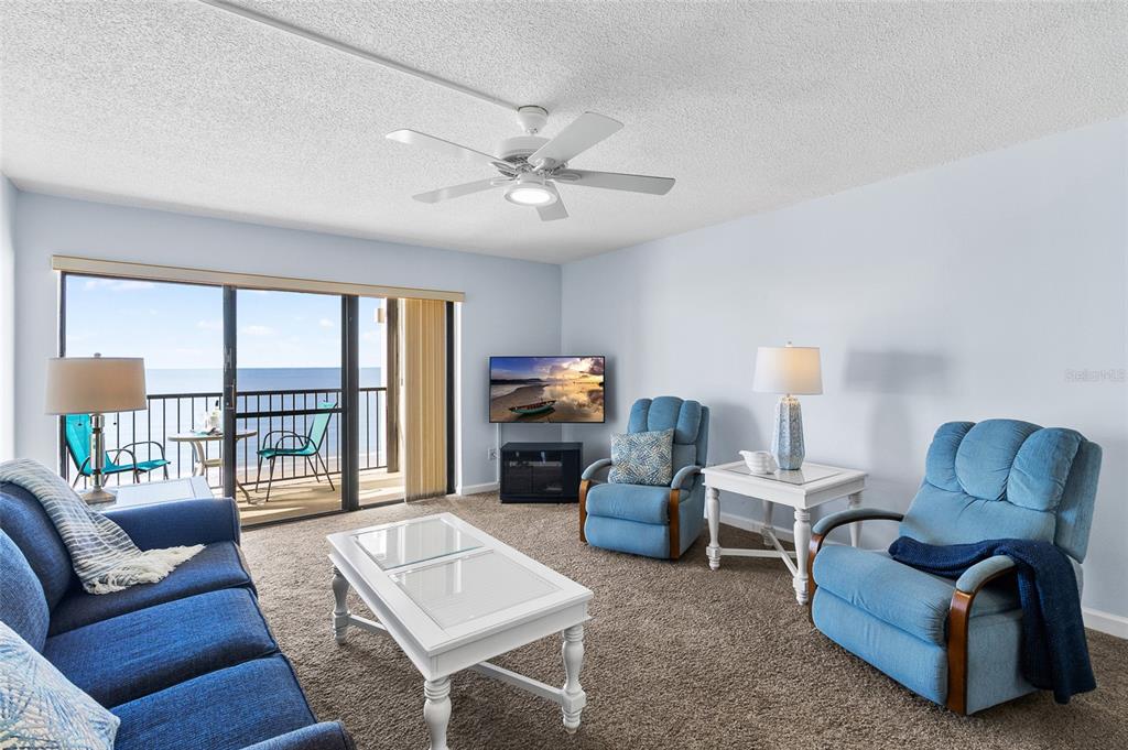 15000 Gulf Boulevard, Unit 605 Madeira Beach, FL 33708 - Photo 15 of 54 a living room with furniture a ceiling fan a fireplace and a large window