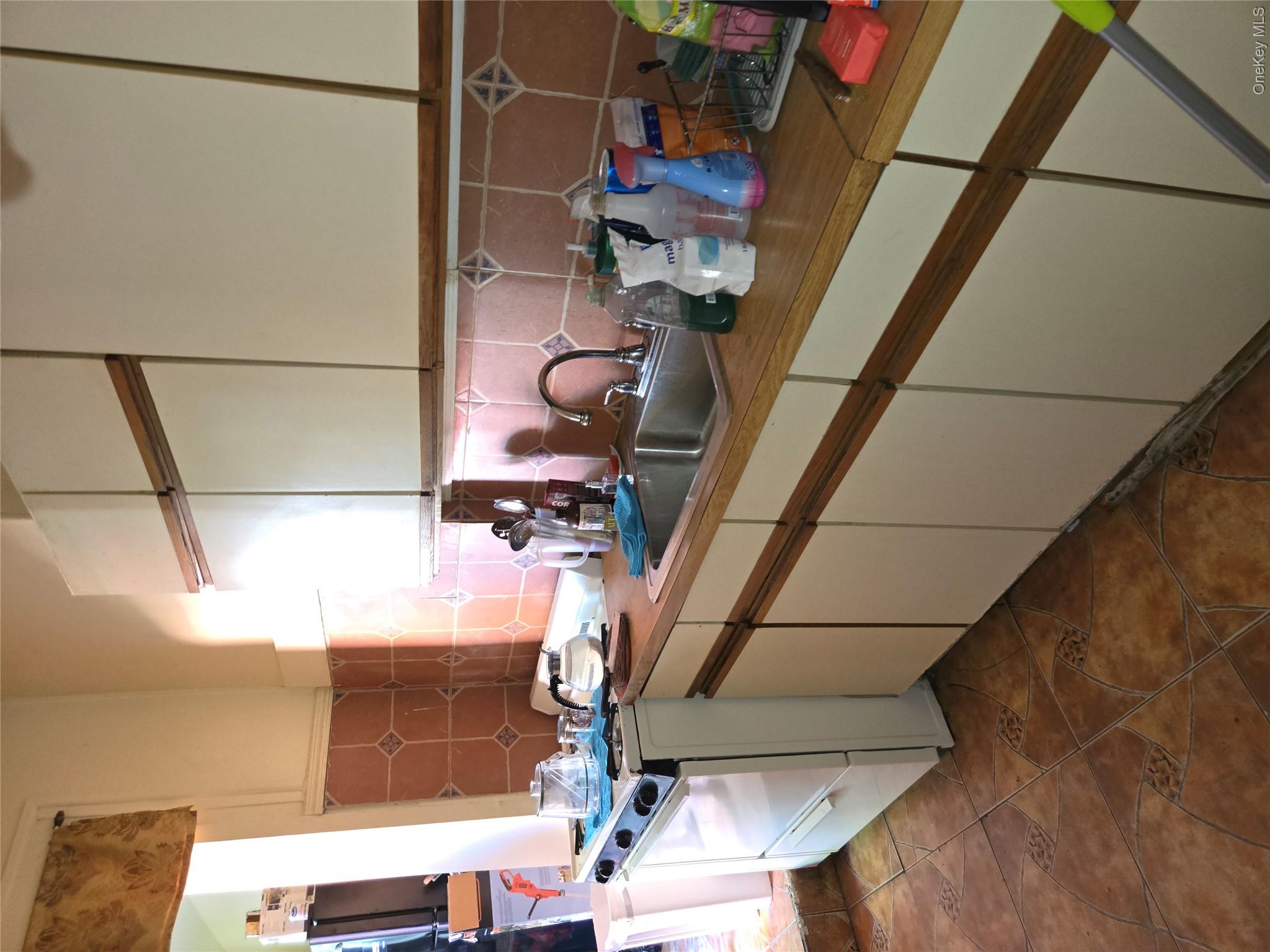 343 Rutland Road Brooklyn, NY 11225 - Photo 13 of 17 Kitchen with range, tasteful backsplash, light countertops, dark tile patterned flooring, and white cabinetry