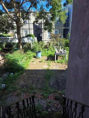 a view of a yard with plants and a brick wall