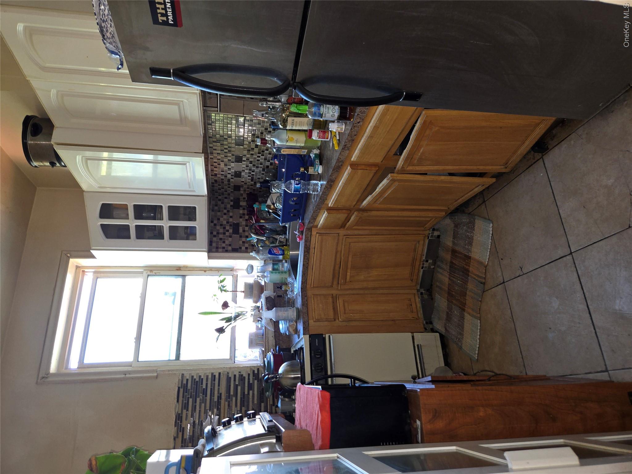343 Rutland Road Brooklyn, NY 11225 - Photo 4 of 17 Kitchen featuring fridge, light tile patterned floors, glass insert cabinets, decorative backsplash, and brown cabinets