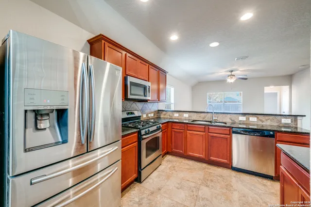 a kitchen with stainless steel appliances granite countertop a refrigerator and a stove top oven