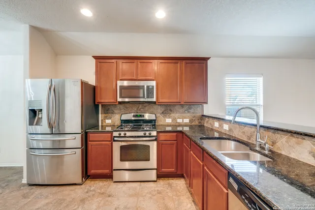 a kitchen with granite countertop a refrigerator stove and sink