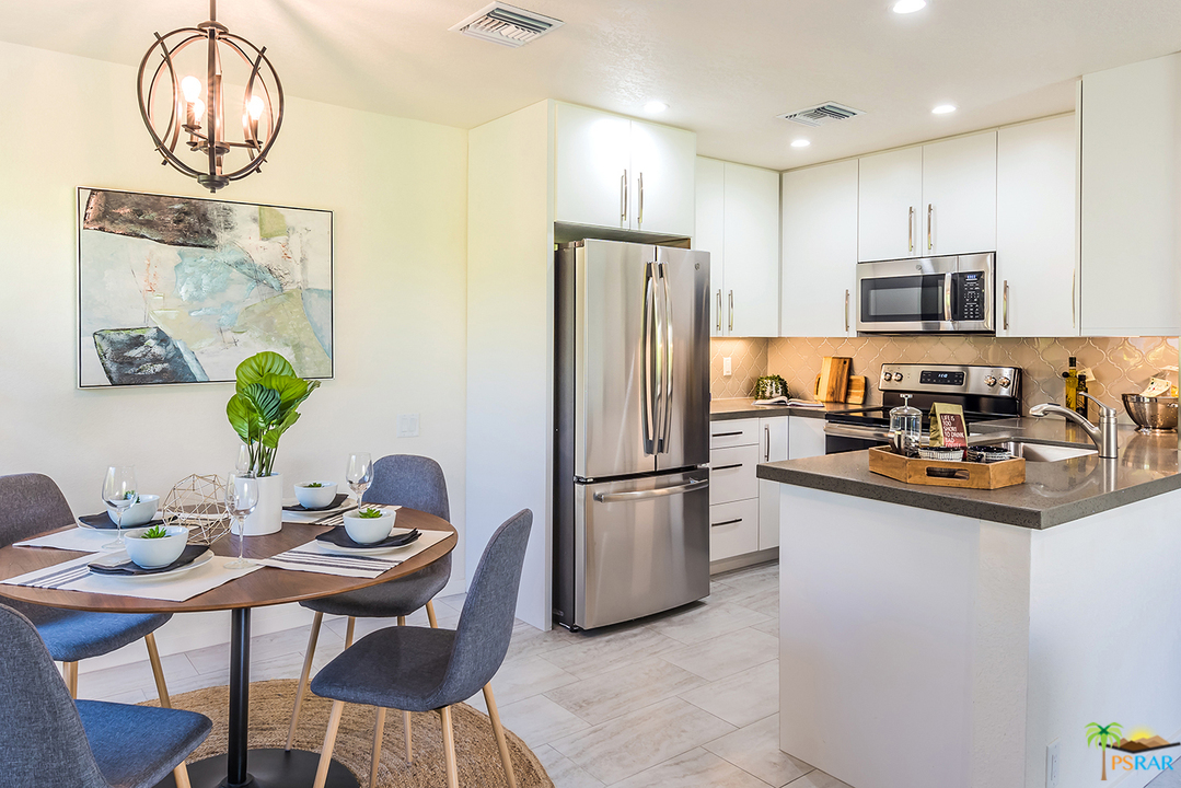 1111 East Ramon Road, Unit 8 Palm Springs, CA 92264 - Photo 7 of 36 a kitchen with stainless steel appliances granite countertop a sink a stove a refrigerator a microwave oven with a dining table and chairs