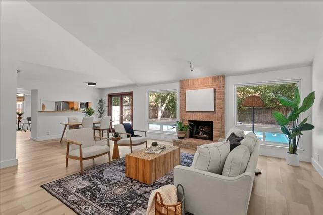 a living room with furniture a fireplace a large window and a flat screen tv