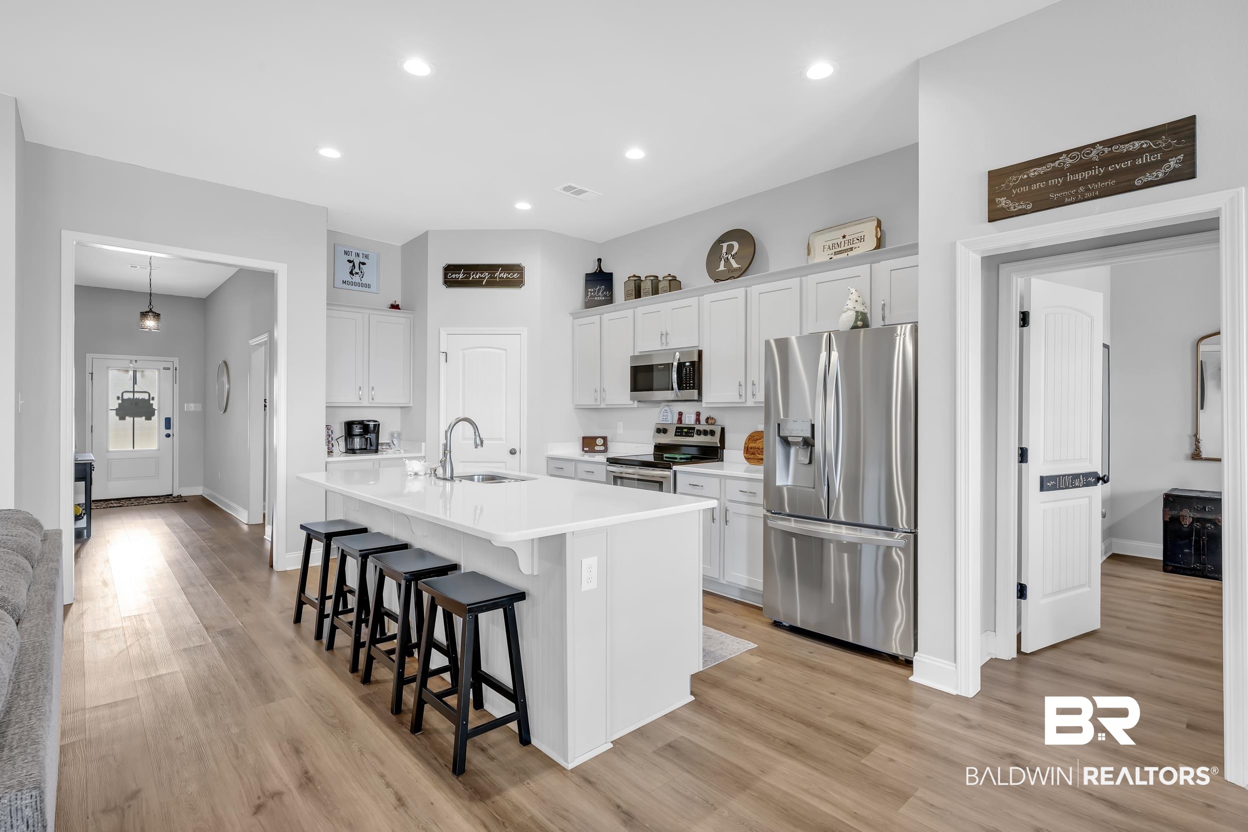 1176 Stella Road Foley, AL 36535 - Photo 10 of 40 Kitchen with stainless steel appliances, white cabinets, a kitchen bar, a kitchen island with sink, and light wood-style flooring