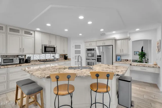 a kitchen with kitchen island granite countertop a sink cabinets and wooden floor