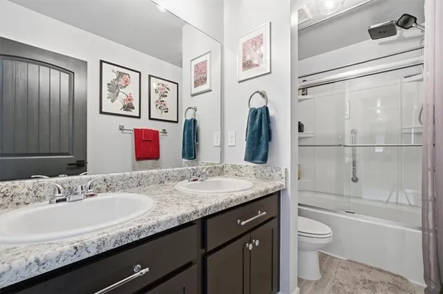 a bathroom with a granite countertop bathtub sink vanity mirror and toilet