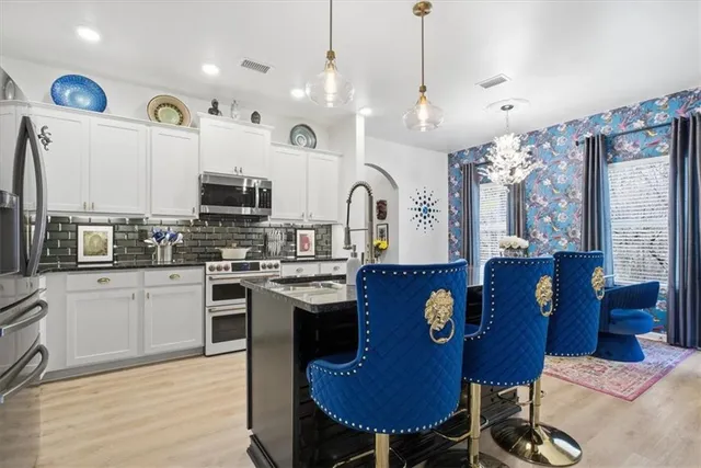 a large kitchen with stainless steel appliances granite countertop a stove a sink dishwasher a dining table and chairs with wooden floor