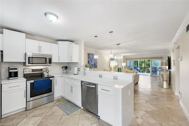 a kitchen with stainless steel appliances kitchen island granite countertop a stove and white cabinets