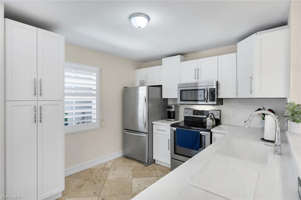 4200 Belair Lane, Unit 316 Naples, FL 34103 - Photo 4 of 18 a kitchen with stainless steel appliances a refrigerator a stove a microwave and cabinets