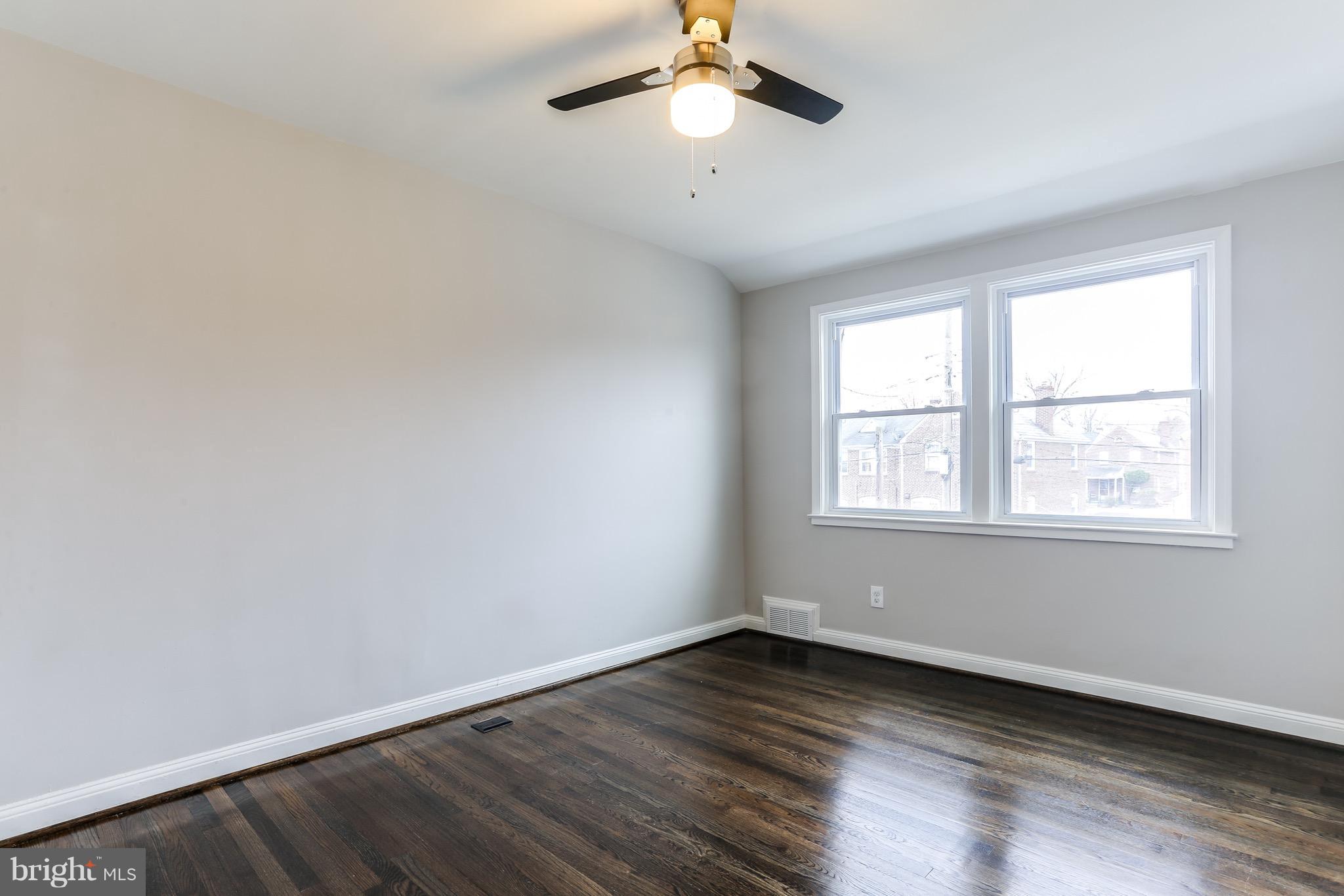 1425 Kitmore Road Baltimore, MD 21239 - Photo 7 of 23 an empty room with wooden floor chandelier fan and windows