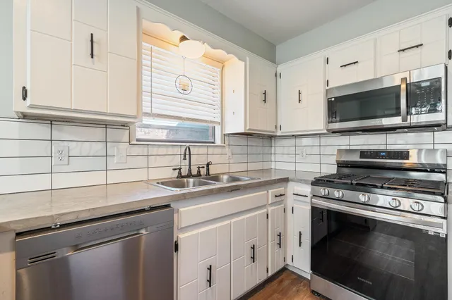 a kitchen with cabinets stainless steel appliances a sink and a window