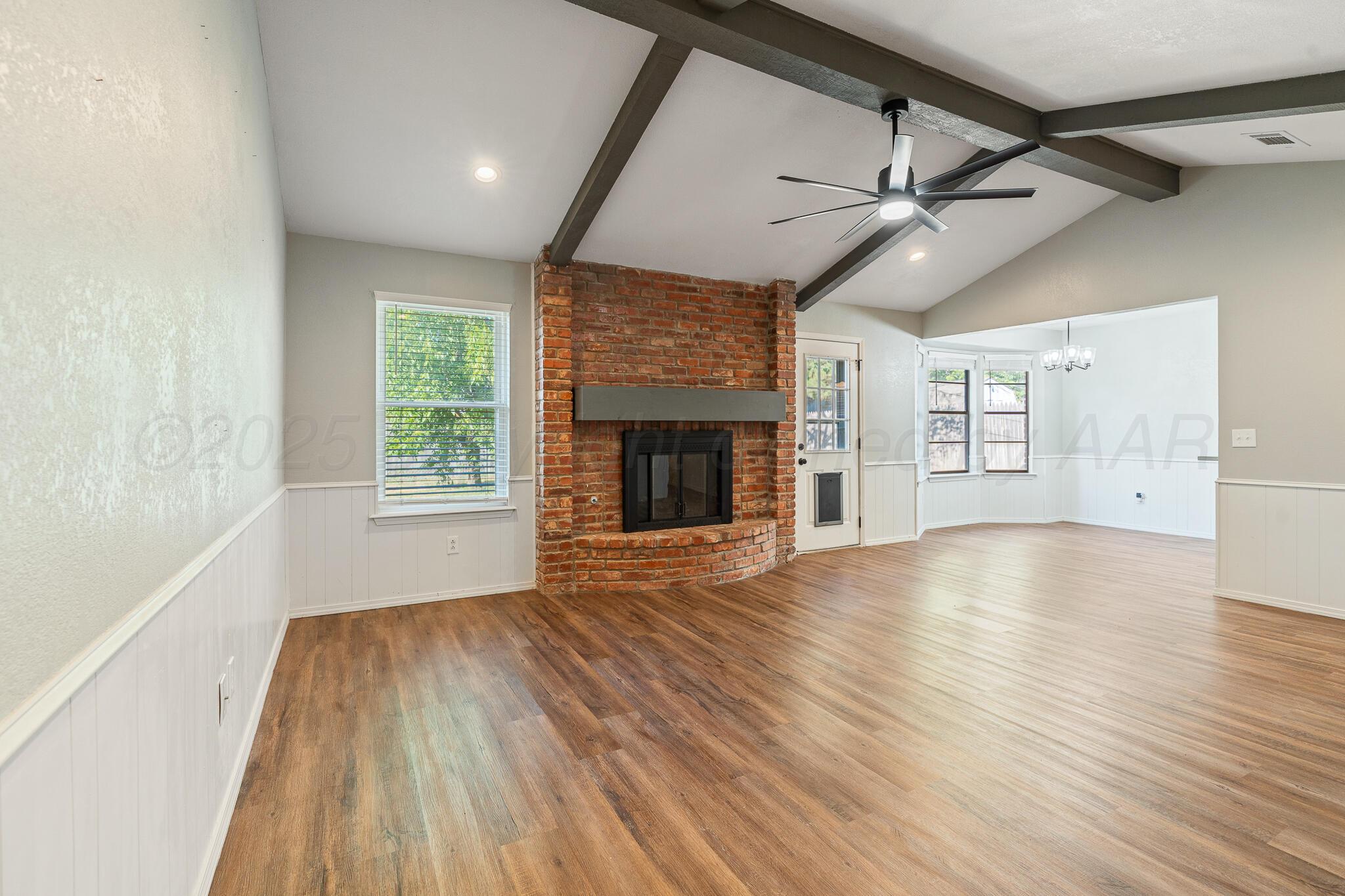 6212 Rutgers Street Amarillo, TX 79109 - Photo 6 of 26 an empty room with wooden floor fireplace and windows