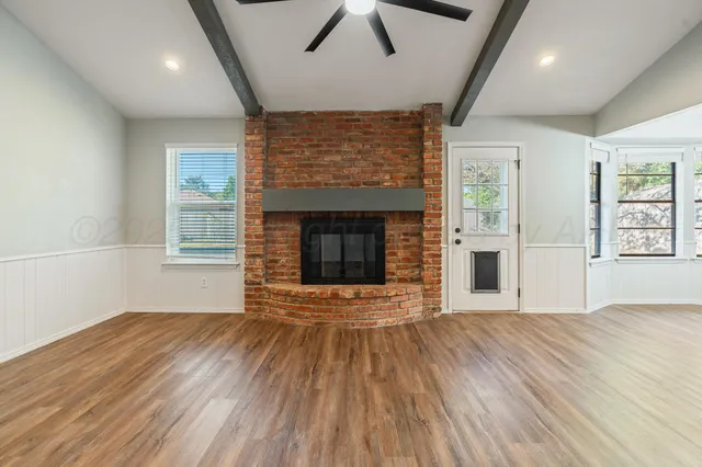 an empty room with wooden floor fireplace and windows