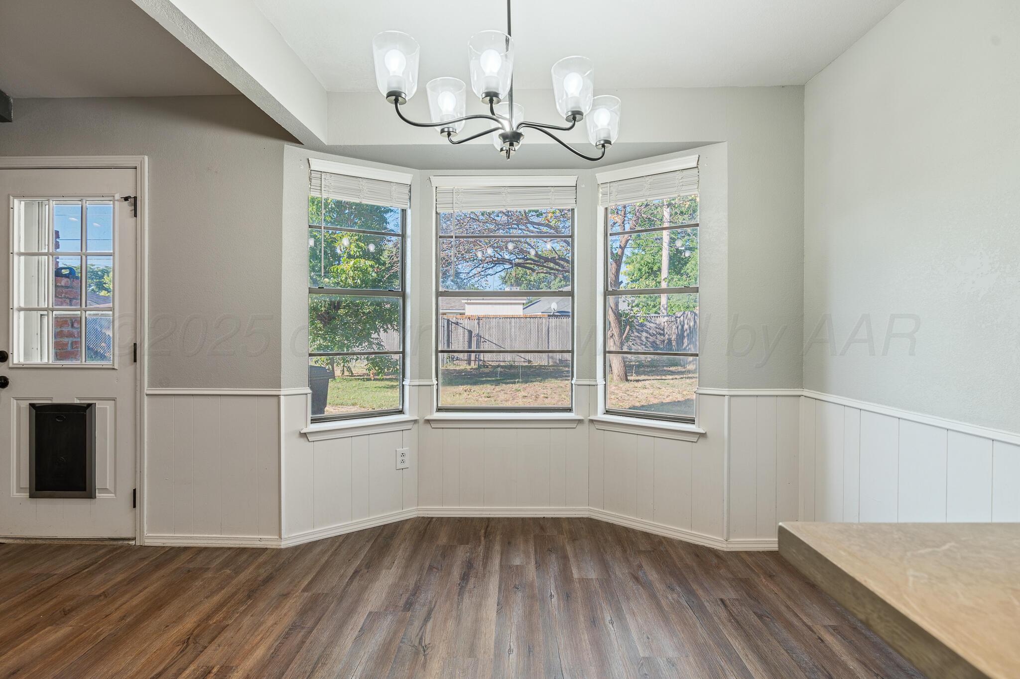 6212 Rutgers Street Amarillo, TX 79109 - Photo 9 of 26 a view of an empty room with wooden floor and a window