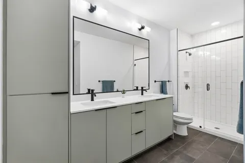a bathroom with a double vanity sink toilet and shower