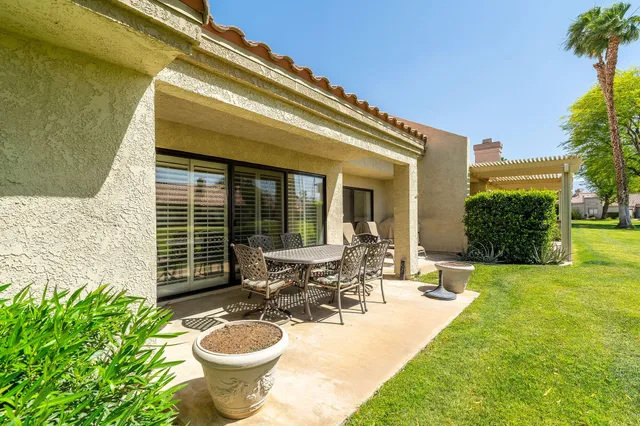 a view of a patio with table and chairs potted plants and a large tree