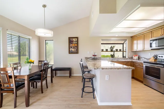 a kitchen with stainless steel appliances granite countertop a stove oven a dining table and chairs with wooden floor