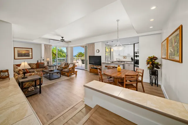 a living room with furniture kitchen view and a wooden floor